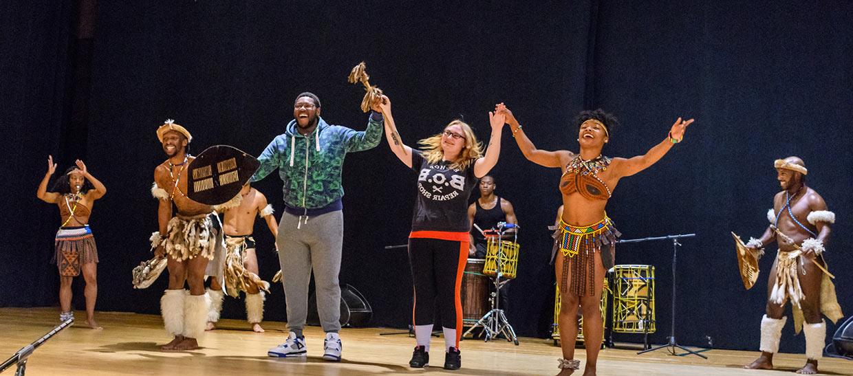 Students with performers from STEP AFRIKA on stage at an event on campus