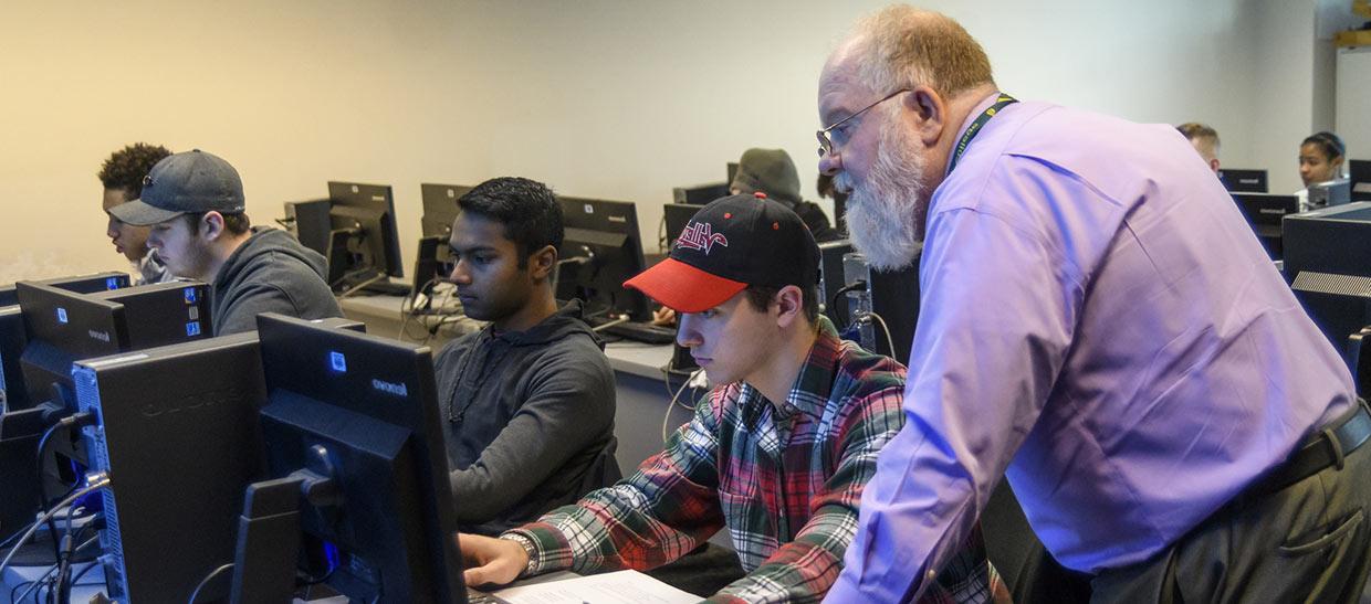 Students working with a professor at a computer