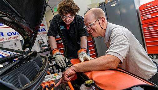 Dr. Chris McNally works with a student on an electric vehicle.