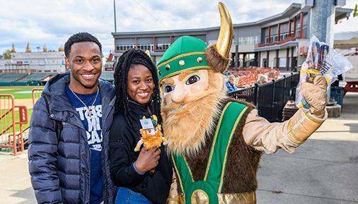 HVCC Viking mascot with two students in the baseball stadium