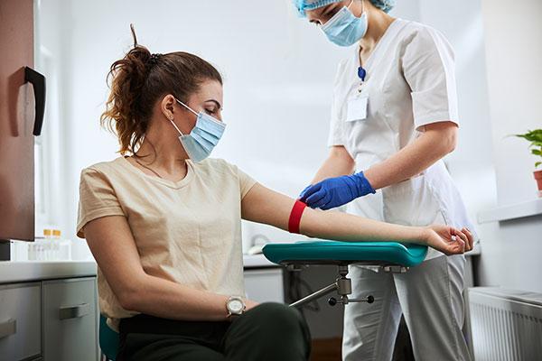 放血技术人员正在给一位女性病人的手臂上绑止血带